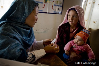 Community midwife in Afghanistan talks with mother (holding baby) about family planning