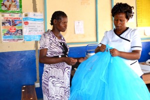 A nurse demonstrates the correct way to use a mosquito net to an expectant mother, Bungoma South County, Kenya