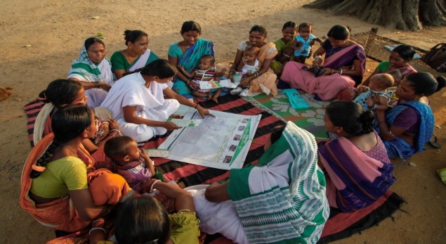 A vaccinator and mothers in India reviewing their community’s MVMH tool