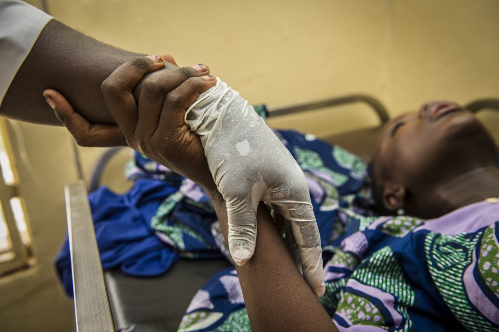 A midwife holds the hand of a woman in labor at a hospital in Gusau, Nigeria