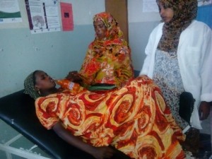 Zerina’s mother offers her a drink during labor while Saada observes the patient’s status