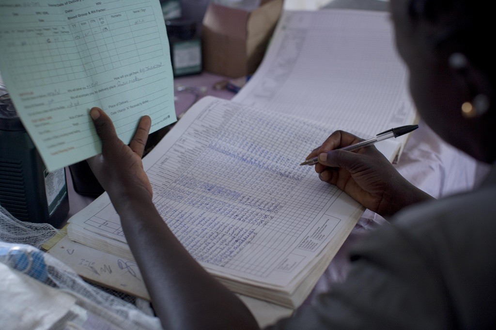 A health care worker fills in a client's reocords at a Primary Health Centre in Mideh in Mundri East County South Sudan