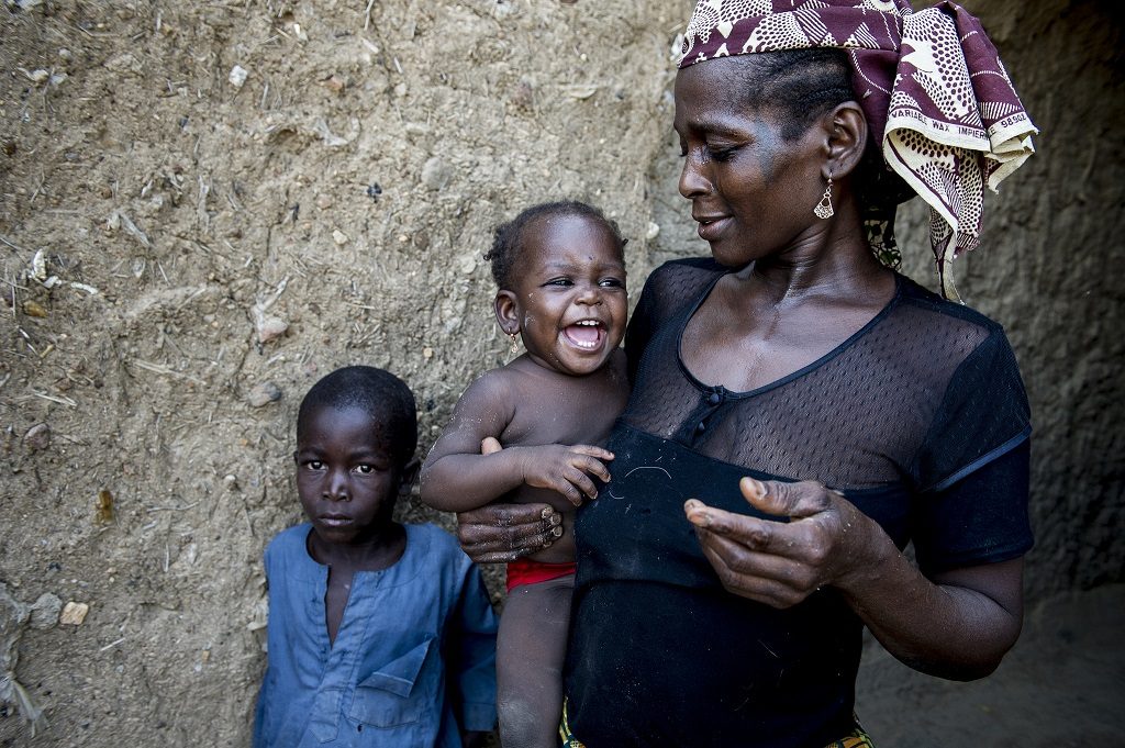Mother in Nigeria holding her baby and child standing next to them