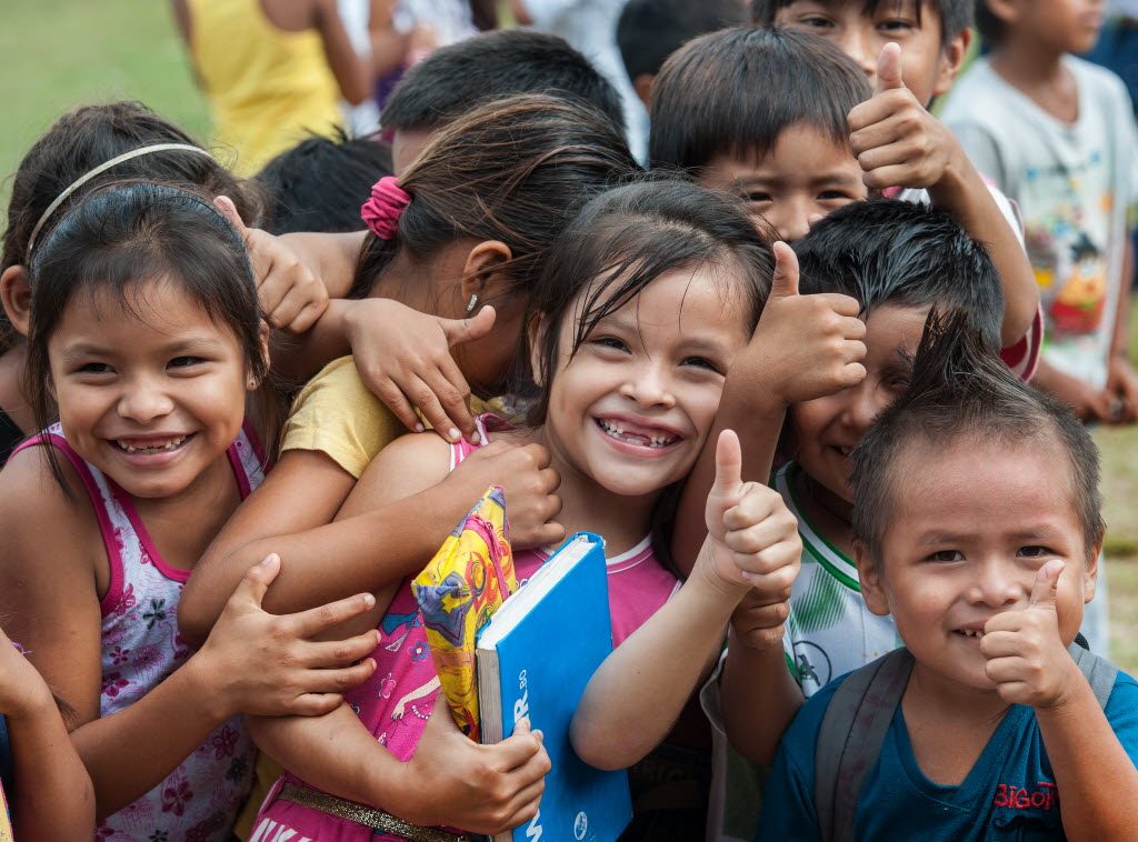 Group of happy children giving the thumbs up signal.