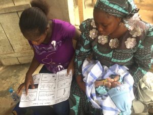 Two young mothers in Nigeria learn how to use chlorhexidine gel with a graphic chart