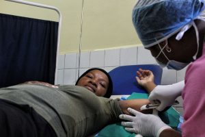 Midwife Sitraka Rasolofomanana, a counselor and postpartum family planning service provider, inserts an implant in Mamy Rasoahariniaina’s arm.