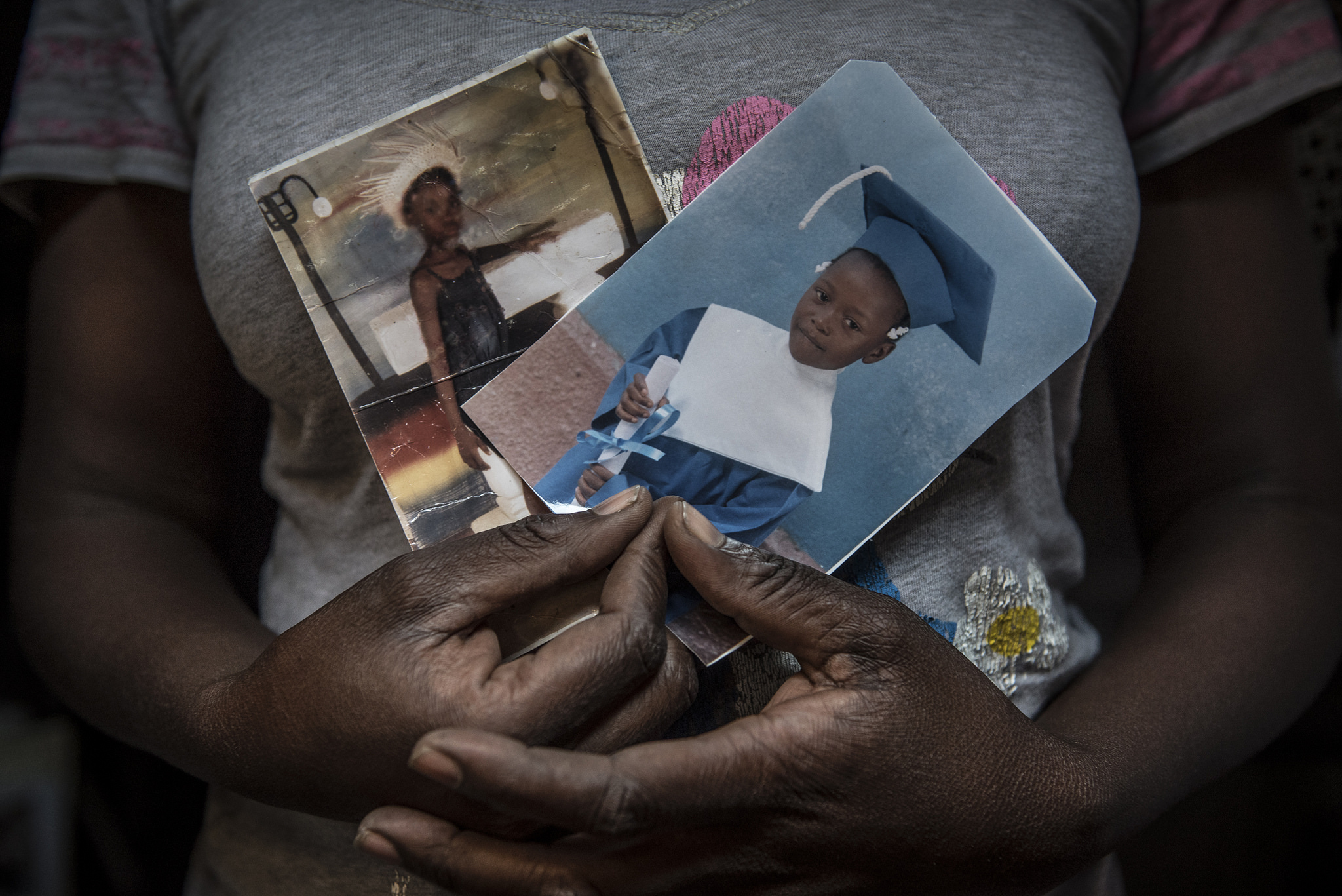 A Haitian mother of three displays pictures of her children, who are in school