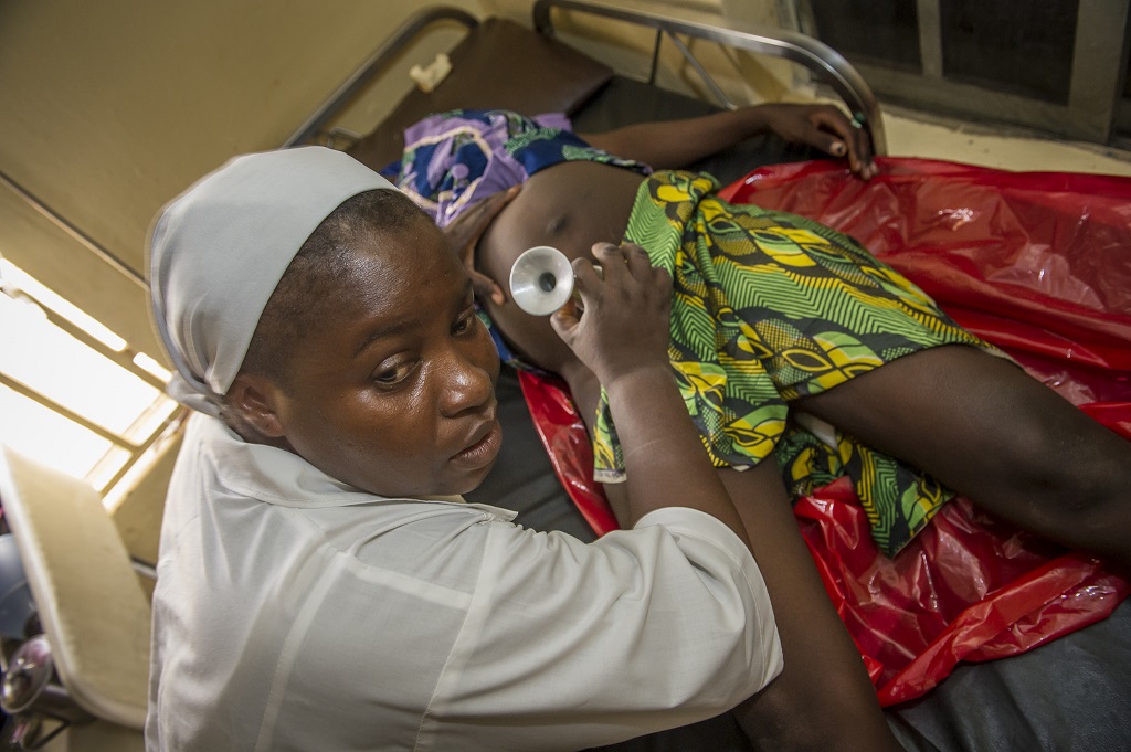 Above: A Nigerian midwife monitors the heart beat of a young mother in prolonged labor at a hospital.