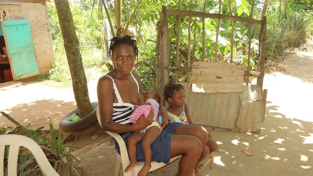 Cléomide and her two daughters in front of their home.