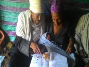 Kes Melakeselam, an Orthodox priest, using a family health guide to educate Abeba Mesele, who recently gave birth to a baby boy. 