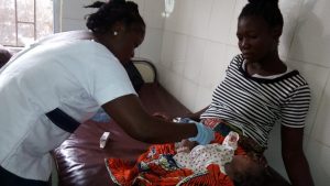 A health worker in Liberia shows a mother how to apply chlorhexidine gel to the cord site to prevent newborn sepsis