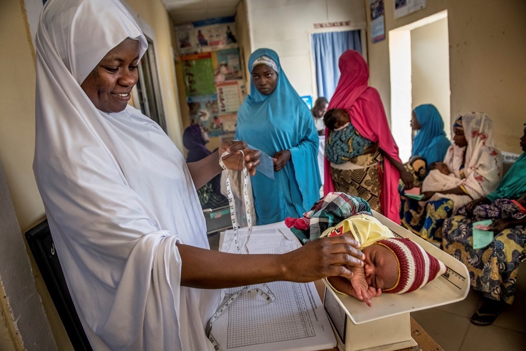 a community health worker measures and weighs Mohammed during his visit