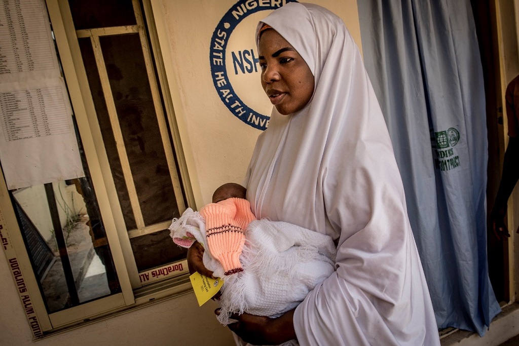 Kayya Abdulkadir arrives to Wandi Clinic with her newborn son, Mohammed, with the card she received during his shaving ceremony.