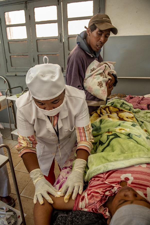 A midwife in Madagascar inserts a postpartum implant in a woman who has just delivered as her husband looks on