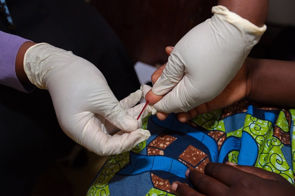A person having their finger pricked for an HIV test.