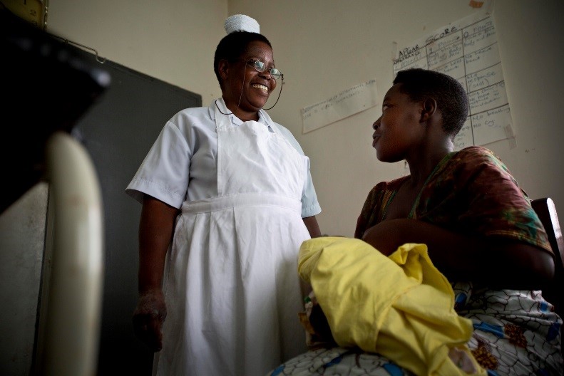 A midwife in Uganda talks with a new mother after her delivery.