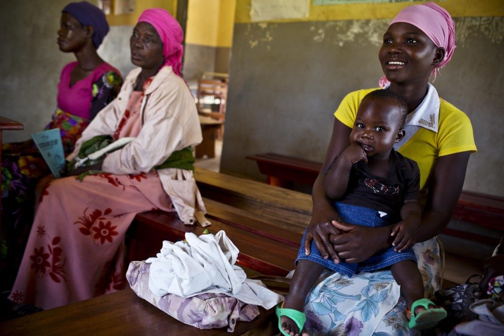 Mothers and children wait for vaccines and basic health services at a health center in Busowobi Iganga, Uganda. (Photo courtesy of Kate Holt/MCSP.)