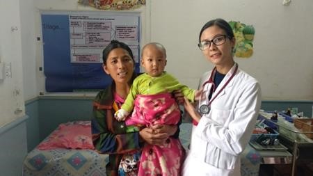 Khant with his mother and Dr. Cho the day of his discharge. The poster behind them help staff recognize danger signs and respond quickly.